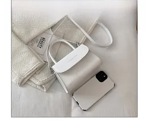 Detailed top view of white mini flap bag with fashion text shown with phone for scale