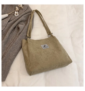 Detailed texture of khaki corduroy tote bag with vintage woven label on soft fabric