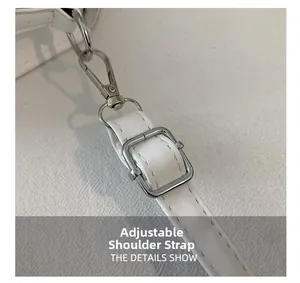 Detail view of the adjustable white leather shoulder strap with silver metal buckle
