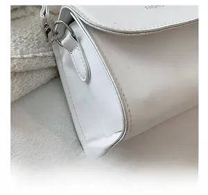 Close-up of fine stitching and embossed 'FASHION' text on white leather handbag