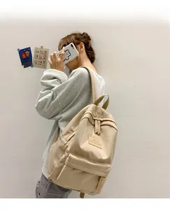 Frau trägt einen beigen Freizeitrucksack mit MRMI Leisure Logo vor schlichtem Hintergrund