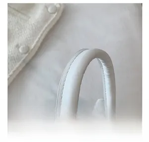 Close-up of white padded top handle with premium stitching on a mini handbag