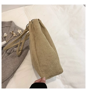 Detail of khaki corduroy tote bag showing ribbed texture and drawstring metal ring closure