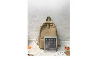 Khaki minimalistischer Rucksack im Größenvergleich mit einem iPad vor einer Wand