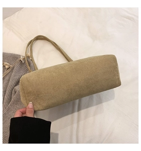 Detailed texture of beige corduroy tote bag showing thick vertical stripes and shoulder strap