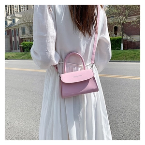 Pink mini square crossbody bag shown on a model in an outdoor urban street setting