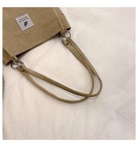 Detail of khaki corduroy tote bag showing silver metal ring handle attachment and label