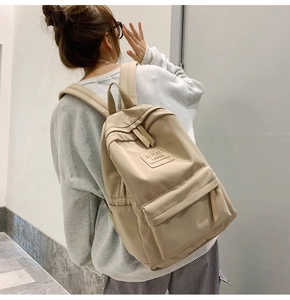 Rückansicht eines Models mit einem beigen minimalistischen Nylon-Rucksack für Schule