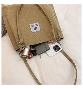 Close-up of corduroy tote bag showing spacious interior with daily essentials and tag