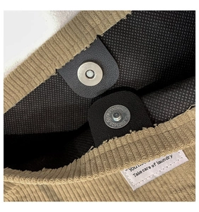 Close-up of corduroy tote bag interior with magnetic closure and woven label