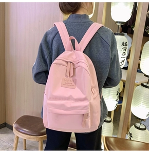 Detail eines hellrosa Nylon-Rucksacks mit MRMI Leisure-Patch in sanfter Innenraumkulisse