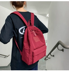 Nahaufnahme eines weinroten Nylon-Rucksacks mit breiten Trägern auf einem Modell