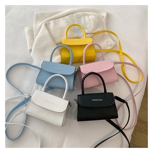 Flat lay of mini crossbody bags in five colors on white bedding, fashion bag detail