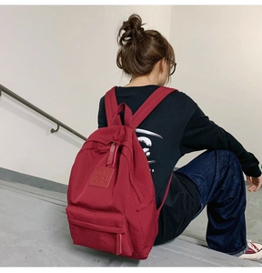 Nahaufnahme dunkelroter wasserdichter Nylonrucksack mit Lederlogo auf grauen Stufen