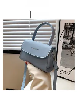 Detail of light blue crossbody bag with curved handle and FASHION & BAG lettering