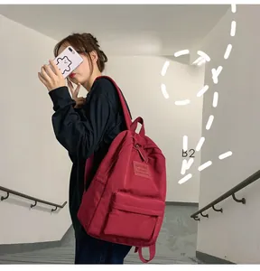 Detail eines weinroten Nylon-Rucksacks mit Reißverschlusstasche und Seitentasche