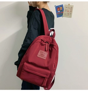 Detail eines weinroten wasserdichten Nylon-Rucksacks mit Vordertasche und Logo