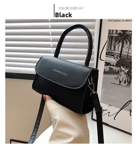 Detail of black leather small square bag with top handle and Fashion & Bag lettering