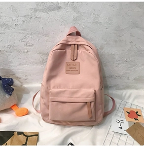 Detailansicht des rosa Nylon-Rucksacks mit Lederlogo und vorderer Reißverschlusstasche