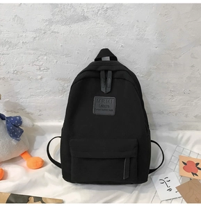 Detaillierte Ansicht des schwarzen Nylon Rucksacks mit großem Fach und Marken-Patch-Detail