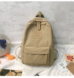 Detailansicht eines großen beigen Canvas-Rucksacks mit Reißverschlussfach und Logo