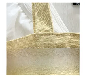 Close-up of reinforced double stitching on beige canvas tote bag with shoulder straps