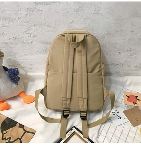 Detail eines khakifarbenen Nylonrucksacks mit verstellbaren Trägern und Tragegriff im Freizeitlook