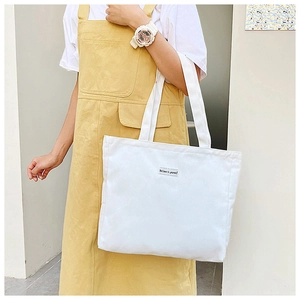 Detailed shot of white canvas tote bag featuring motivational square label design