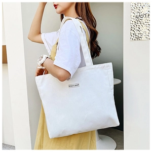 Detail of white canvas tote bag featuring an embroidered Believe in Yourself text label