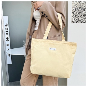 Detail of cream canvas tote bag featuring an inspirational white woven label tag