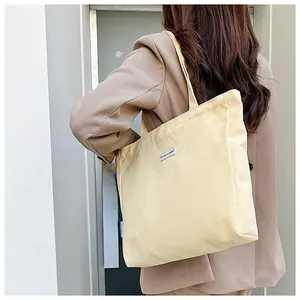 Detail of light yellow canvas tote bag with decorative patch on a shoulder strap