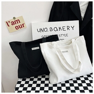 Detail of minimalist canvas tote bags in black and white with slogan labels