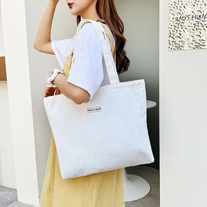 Minimalist white canvas tote bag with Believe in yourself slogan on model shoulder