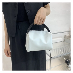 Detail of light blue fabric handbag with black handle and silver zipper closure