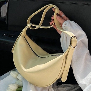 Detail of light yellow crescent shoulder bag in lychee texture leather with gold buckle