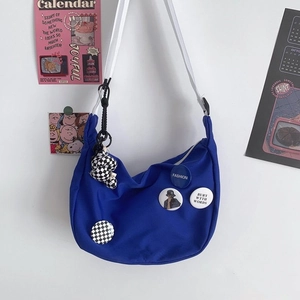 Detail of navy blue canvas hobo bag with patches and checkerboard bear charm