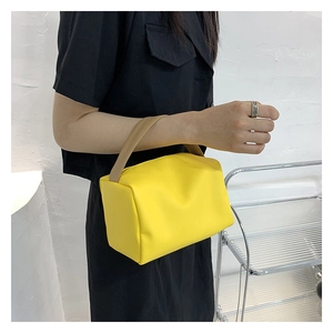 Detail of a bright yellow candy-colored rectangular handbag with khaki top handle strap
