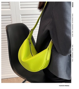 Close-up of neon green crescent shoulder bag with grain texture and metal zipper