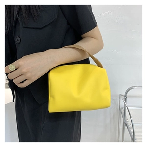 Model side view of bright yellow mini leather handbag with brown leather handles