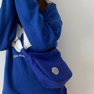Close-up of Klein blue nylon crossbody bag with a checkerboard badge detail