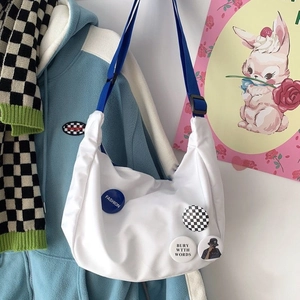 Detail of white nylon messenger bag with blue wide strap and trendy pins and badges