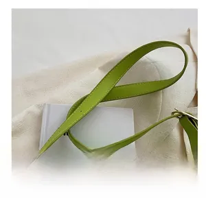 Detail of green faux leather strap with neat stitching and golden metal buckle hardware