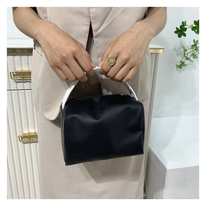 Detail of a modern black square handbag with contrasting white handle and gold zipper