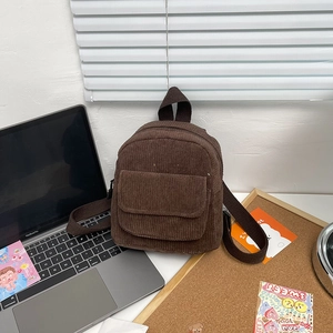 Detail of dark brown corduroy mini backpack fabric texture and front flap pocket