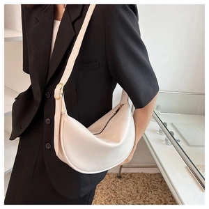 Detail of a cream faux leather hobo bag with gold adjustable buckle on a shoulder strap