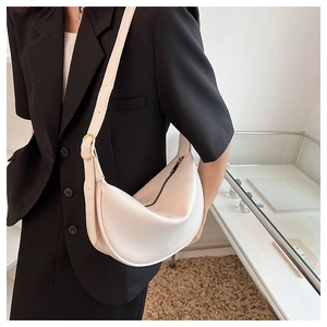 Close-up of minimalist cream half-moon hobo bag with gold zipper and adjustable strap