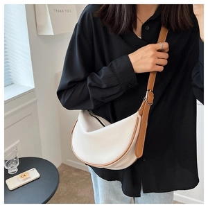Detail of white crescent crossbody bag with brown leather trim and adjustable shoulder strap