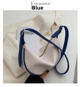 Blue and cream minimalist leather hobo bag with gold hardware and adjustable strap detail