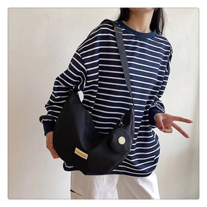 Detail of black crescent crossbody bag with detachable mini pouch and fashion label