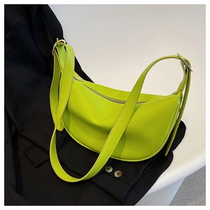 Detail of neon green leather crescent bag with silver zipper on a black blazer